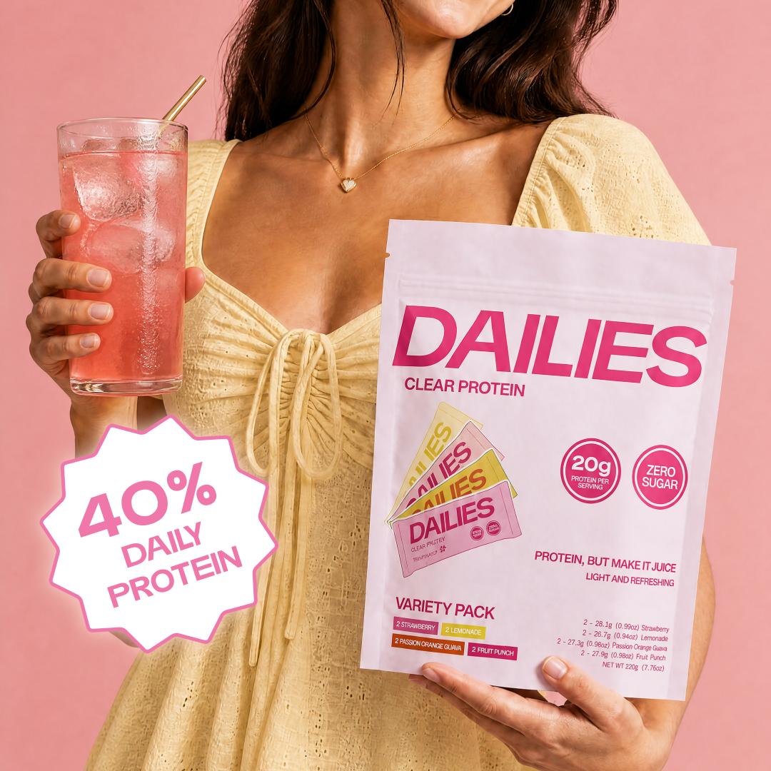 Woman in a yellow dress holding a pink iced drink and Dailies Clear Protein Variety Pack pouch; badge reads 40% daily protein. #flavor_variety-pack